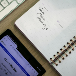 Top view of a notebook, tablet, and keyboard used for social media marketing planning.